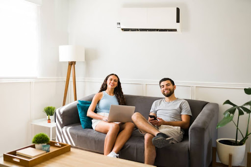 Couple sitting in the living room couch under their AC unit.